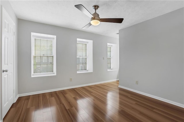 unfurnished room with dark hardwood / wood-style flooring, ceiling fan, a textured ceiling, and a healthy amount of sunlight