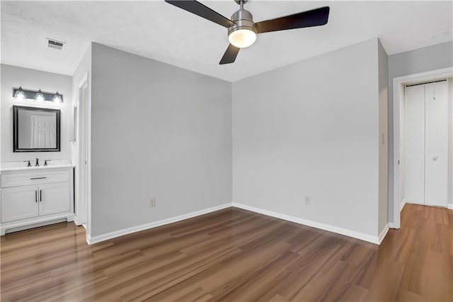 unfurnished bedroom with ceiling fan, ensuite bathroom, sink, and hardwood / wood-style floors