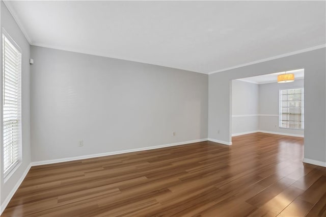 empty room with dark hardwood / wood-style flooring, a wealth of natural light, and ornamental molding