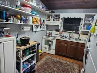 kitchen featuring white electric range, hardwood / wood-style flooring, dark brown cabinets, and sink