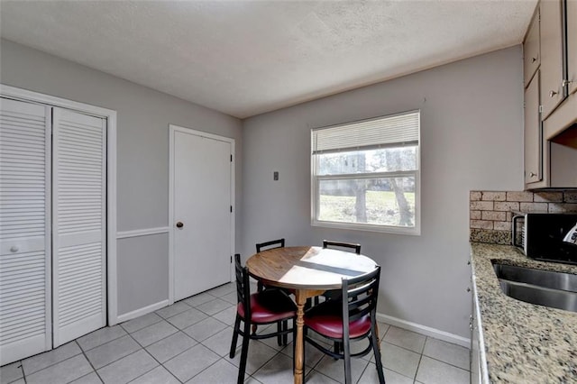 dining space with sink, a fireplace, a textured ceiling, and light tile patterned floors