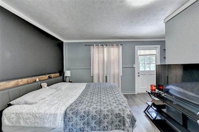 bedroom featuring crown molding, a textured ceiling, and light wood-type flooring