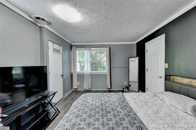 bedroom with crown molding, a textured ceiling, and hardwood / wood-style flooring