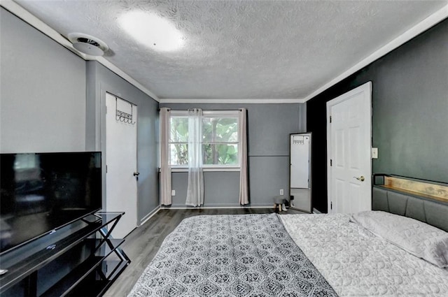 bedroom with crown molding, a textured ceiling, and hardwood / wood-style flooring