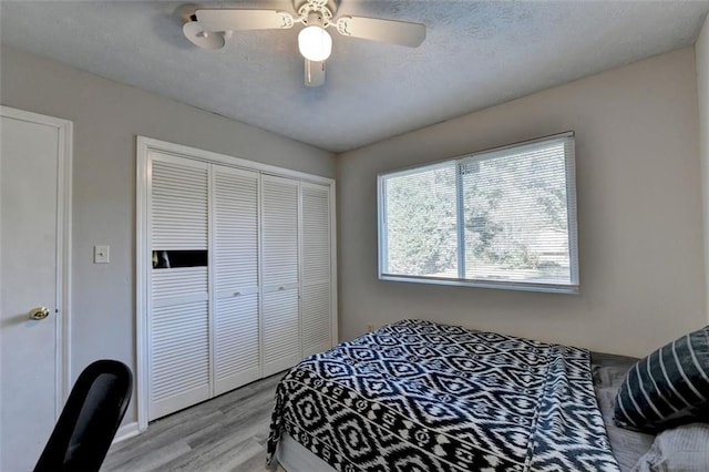 bedroom featuring a closet, a textured ceiling, light wood-type flooring, and ceiling fan