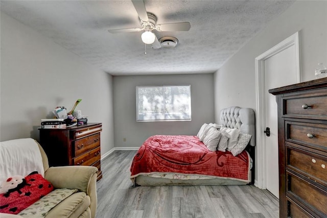 bedroom with ceiling fan, a textured ceiling, and light wood-type flooring