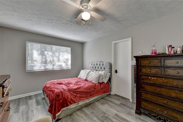 bedroom featuring light hardwood / wood-style floors, a textured ceiling, and ceiling fan