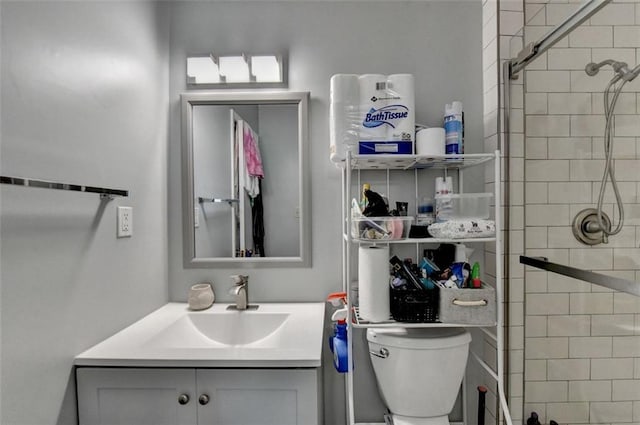 bathroom with vanity, tiled shower, and toilet