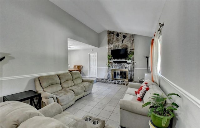 living room with a stone fireplace, light tile patterned floors, and vaulted ceiling