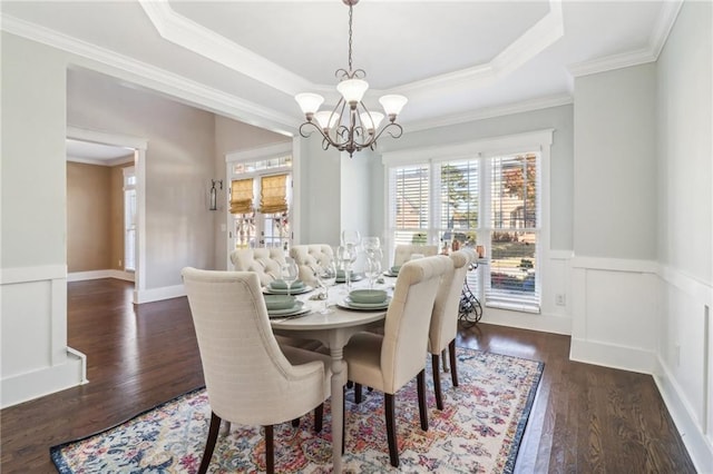 dining area with dark hardwood / wood-style floors, ornamental molding, a tray ceiling, and an inviting chandelier