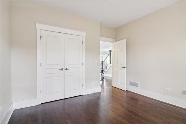 unfurnished bedroom featuring dark hardwood / wood-style floors and a closet