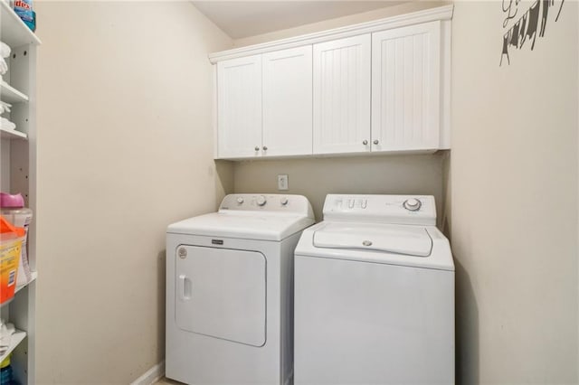 clothes washing area with washing machine and dryer and cabinets