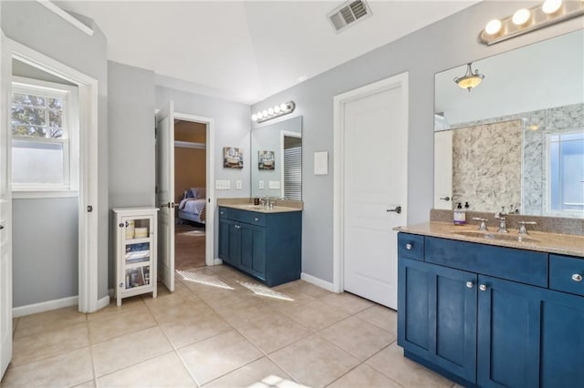 bathroom with tile patterned floors, vanity, and a healthy amount of sunlight