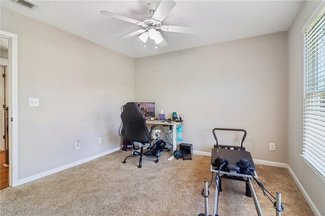 carpeted home office featuring ceiling fan