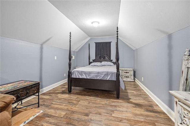 bedroom with baseboards, vaulted ceiling, and wood finished floors