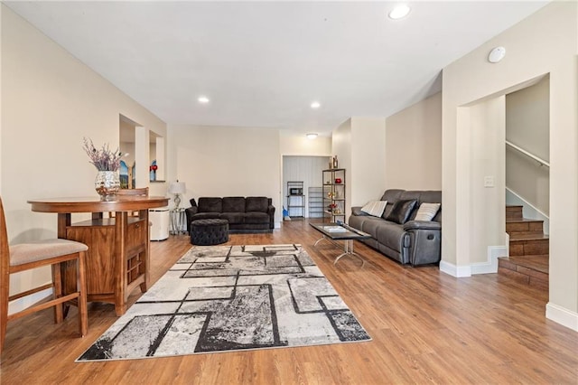 living area with recessed lighting, baseboards, stairway, and wood finished floors