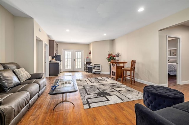 living area featuring heating unit, recessed lighting, french doors, and light wood-style floors