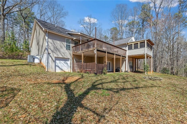 rear view of house featuring central air condition unit, a lawn, a deck, and an attached garage