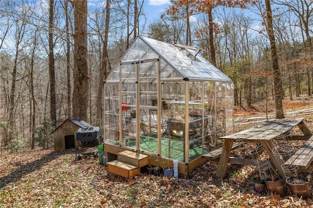 view of greenhouse featuring a wooded view