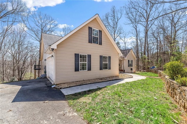view of home's exterior featuring an attached garage, aphalt driveway, and a yard