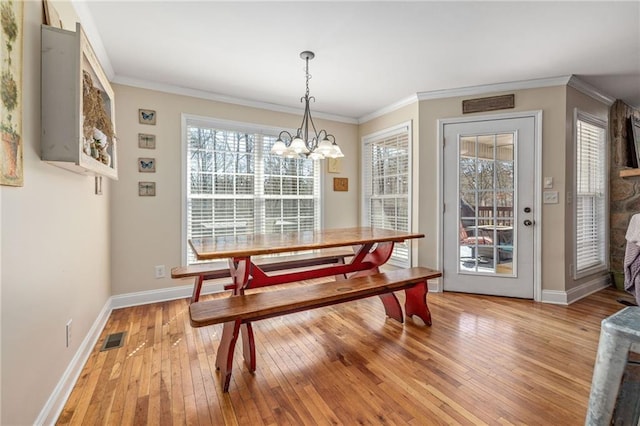 dining area featuring ornamental molding, visible vents, a chandelier, and light wood finished floors