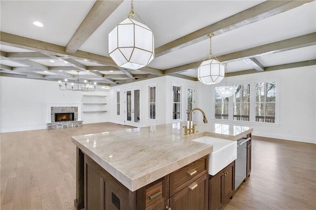 kitchen with a fireplace, decorative light fixtures, dishwasher, sink, and a center island with sink