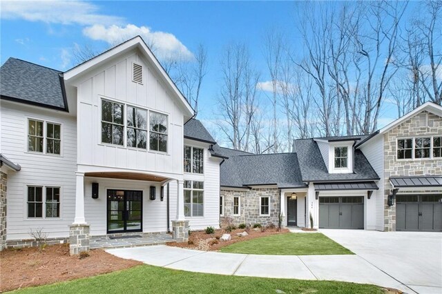 modern inspired farmhouse with a garage and a front lawn