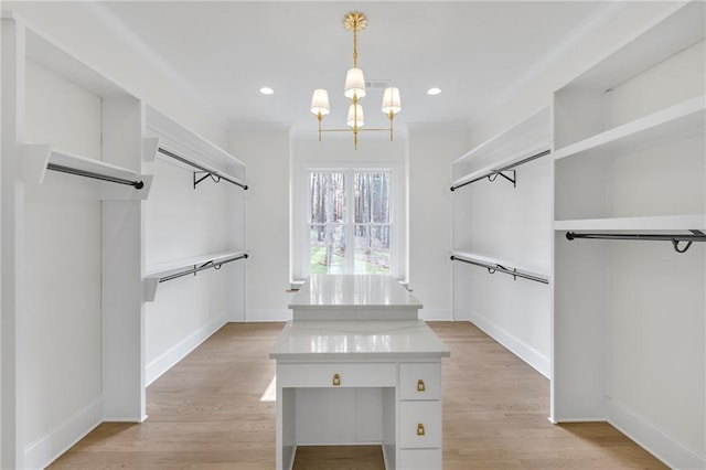 walk in closet with an inviting chandelier and light hardwood / wood-style flooring