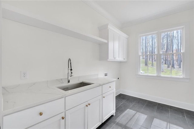 kitchen featuring sink, ornamental molding, dark tile patterned flooring, light stone countertops, and white cabinets