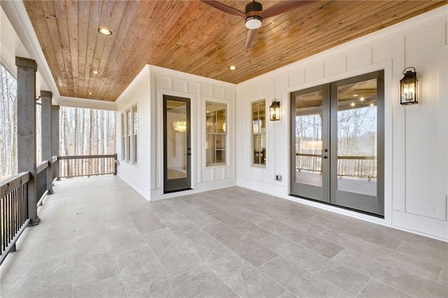 unfurnished sunroom featuring wood ceiling, plenty of natural light, french doors, and ceiling fan