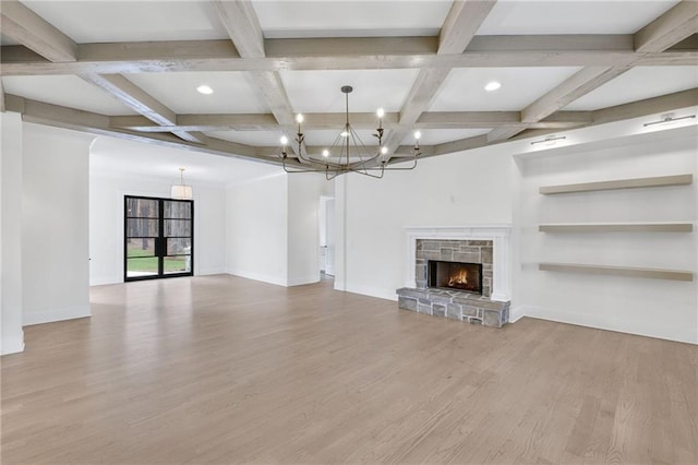 unfurnished living room featuring coffered ceiling, beam ceiling, light wood-type flooring, a notable chandelier, and a fireplace