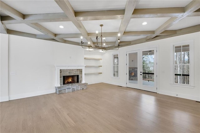 unfurnished living room featuring coffered ceiling, a stone fireplace, a chandelier, beamed ceiling, and hardwood / wood-style floors