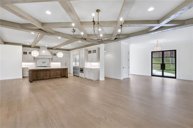 kitchen featuring a large island, pendant lighting, white cabinetry, wood-type flooring, and custom range hood