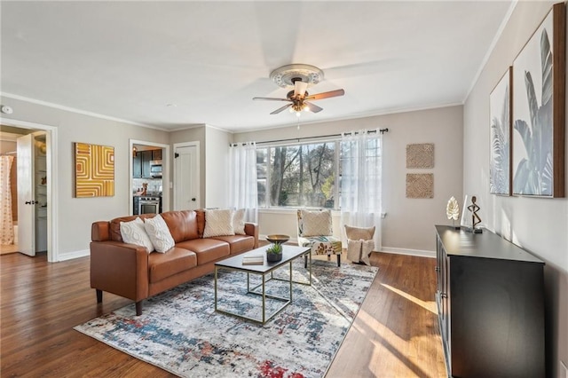 living area with ornamental molding, dark wood finished floors, baseboards, and ceiling fan