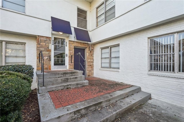 view of exterior entry with brick siding and stucco siding