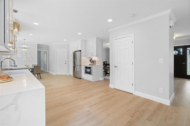 1661 Duxbury Ln NW, Kennesaw, GA 30152 - kitchen with freestanding refrigerator, ornamental molding, a sink, white cabinetry, and light wood-style floors