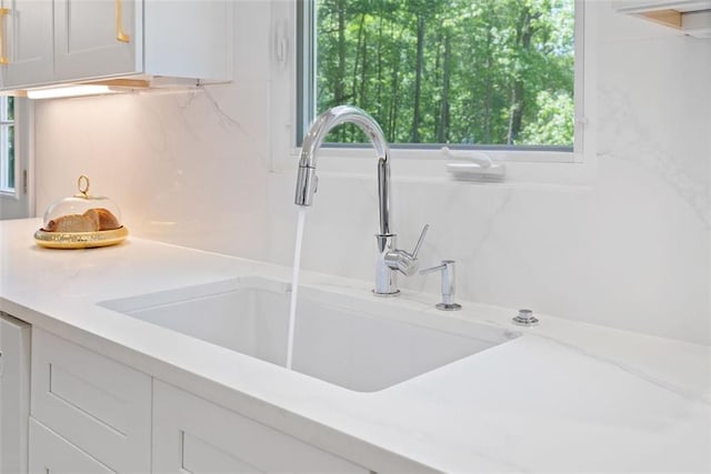 1661 Duxbury Ln NW, Kennesaw, GA 30152 - kitchen view of a sink, white cabinetry, tasteful backsplash, and light stone countertops