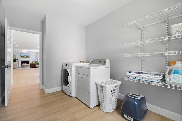 1661 Duxbury Ln NW, Kennesaw, GA 30152 - laundry area featuring washer and clothes dryer, light wood finished floors, baseboards, and a lit fireplace