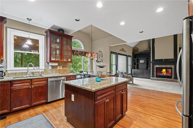 4842 Registry Dr NW, Kennesaw, GA 30152 - kitchen with stainless steel appliances, a sink, hanging light fixtures, light wood-style flooring, and a brick fireplace
