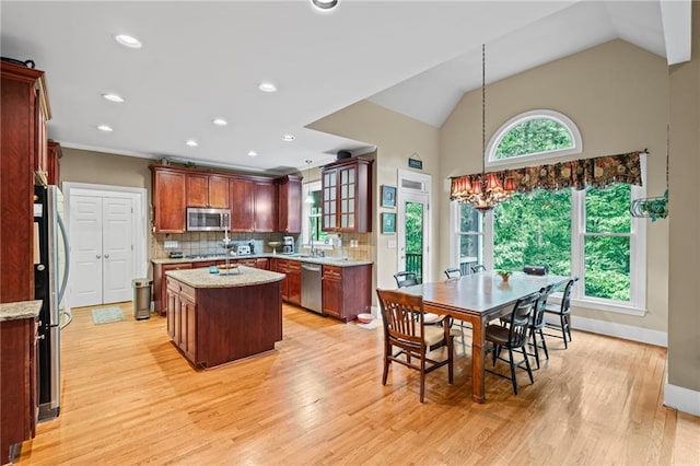 4842 Registry Dr NW, Kennesaw, GA 30152 - kitchen with appliances with stainless steel finishes, a kitchen island, light wood-type flooring, decorative backsplash, and hanging light fixtures