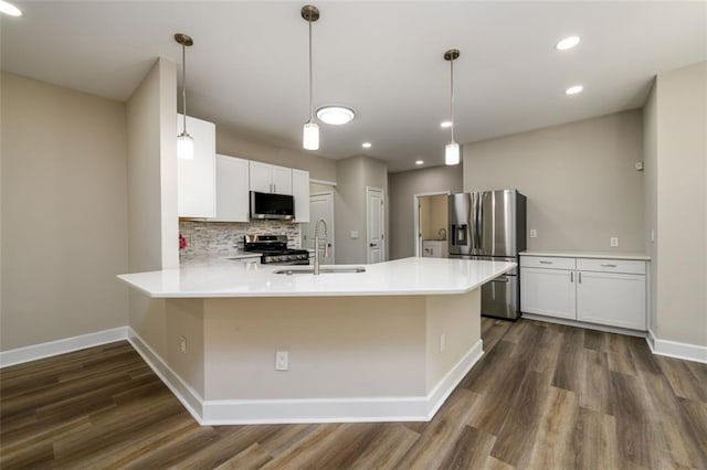 620 Reeves Hill Pt, Lawrenceville, GA 30043 - kitchen featuring stainless steel appliances, a sink, a peninsula, dark wood-type flooring, and baseboards
