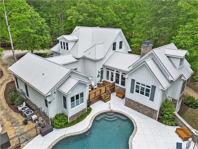 8901 Watkins Mill Rd, Winston, GA 30187 - back of house with board and batten siding, metal roof, a chimney, a fenced backyard, and a view of trees