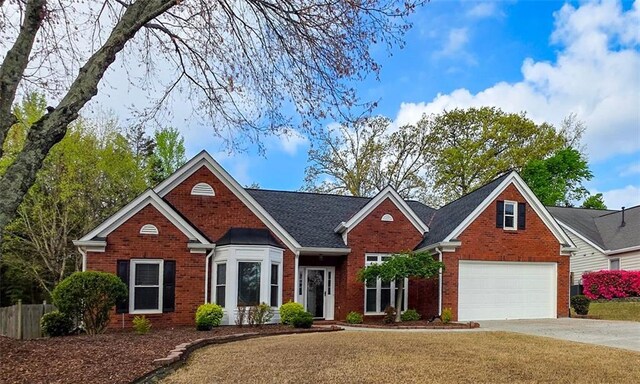 traditional home with fence, a garage, brick siding, and concrete driveway