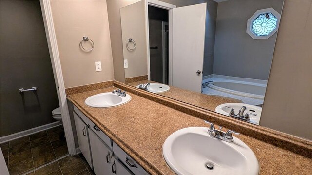 bathroom with tile patterned flooring, vanity, toilet, and a tub to relax in