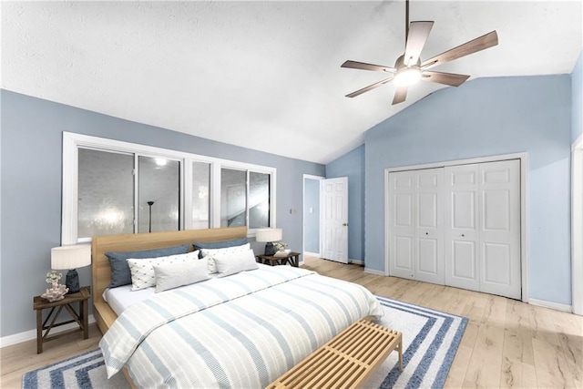 bedroom featuring lofted ceiling, baseboards, light wood-style floors, a closet, and ceiling fan