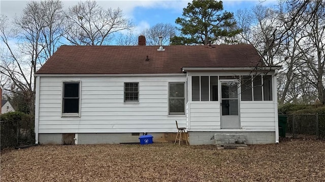 rear view of house featuring a shingled roof, fence, a sunroom, crawl space, and a chimney