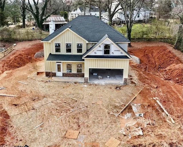 view of front of home with driveway, roof with shingles, board and batten siding, and an attached garage