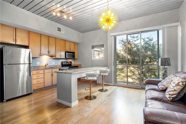 kitchen with light stone countertops, decorative light fixtures, stainless steel fridge, electric range oven, and a kitchen breakfast bar