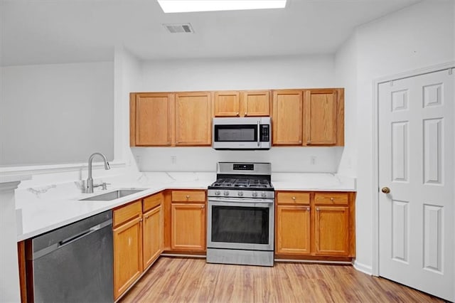 kitchen featuring visible vents, light countertops, appliances with stainless steel finishes, light wood-style floors, and a sink