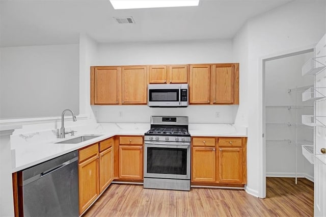 kitchen with visible vents, light countertops, light wood-type flooring, appliances with stainless steel finishes, and a sink